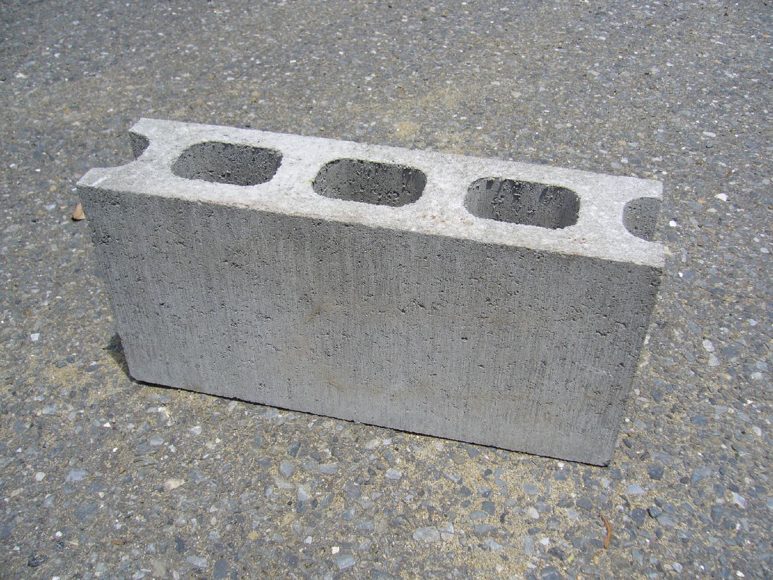 Grey hollow concrete masonry block showing its cavities and textured faces — reference photo, not the exact supplied product